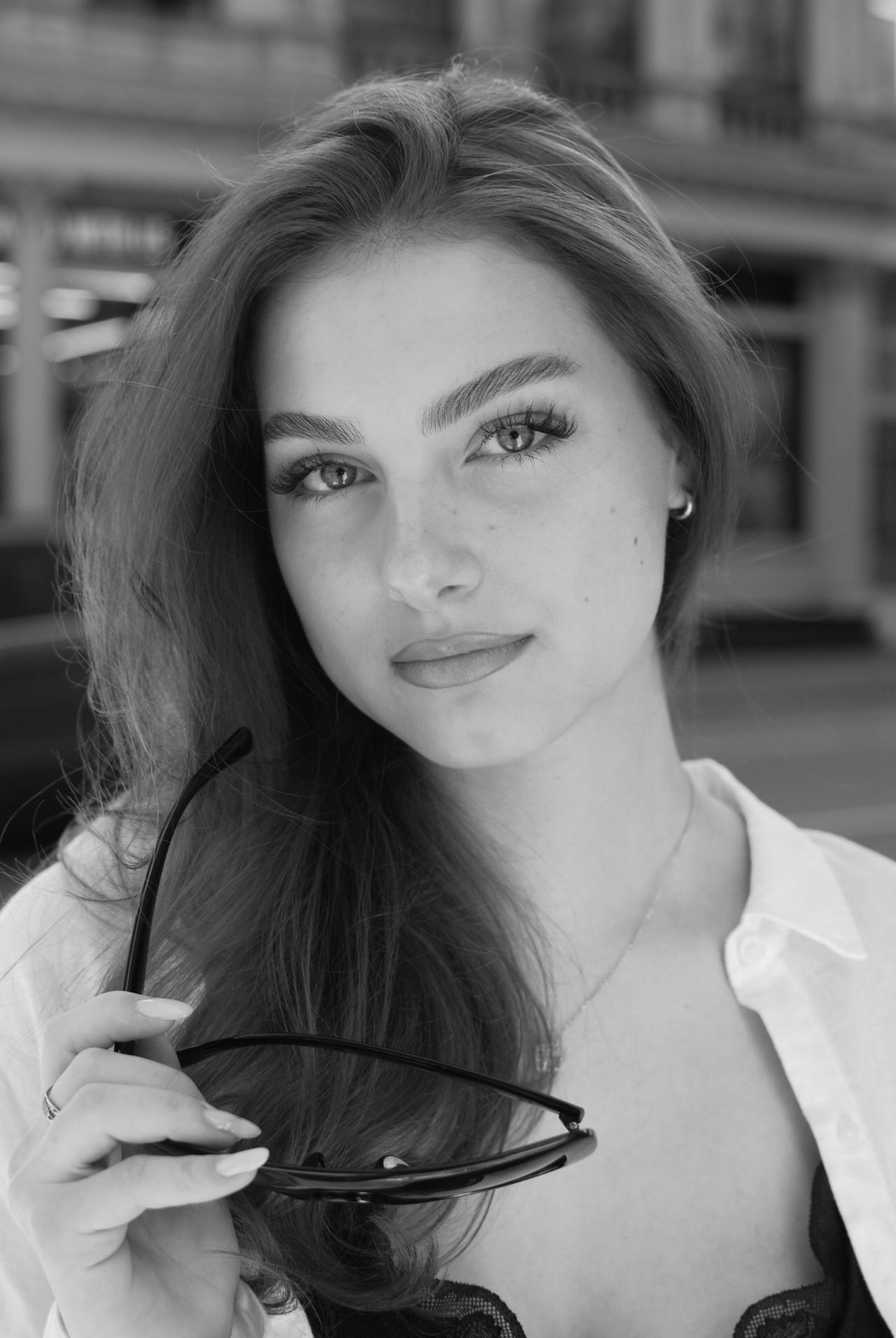 Black and white close-up portrait of Mia Fantalin holding a pair of sunglasses